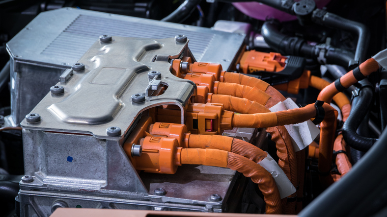 Powerful orange cables connecting the electric vehicle engine, inverter, traction battery and air conditioning compressor. EV maintenance concept. die-cut insulators